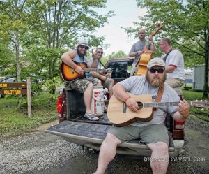guys riding in the back of a truck at ace adventure resort at mountain music festival playing guitar