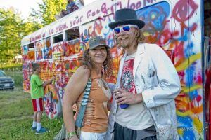 brian zickafoose and wife posing for camera in front of the magic bus at mountain music festival on wonderland mountain at ACE Adventure Resort