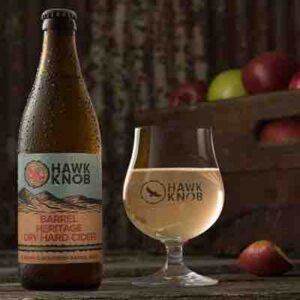 hawk knob hard cider barrel aged in bottle and glass with apples in background