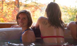 three girls hanging out in a hot tub at one of ace adventure resorts cabins