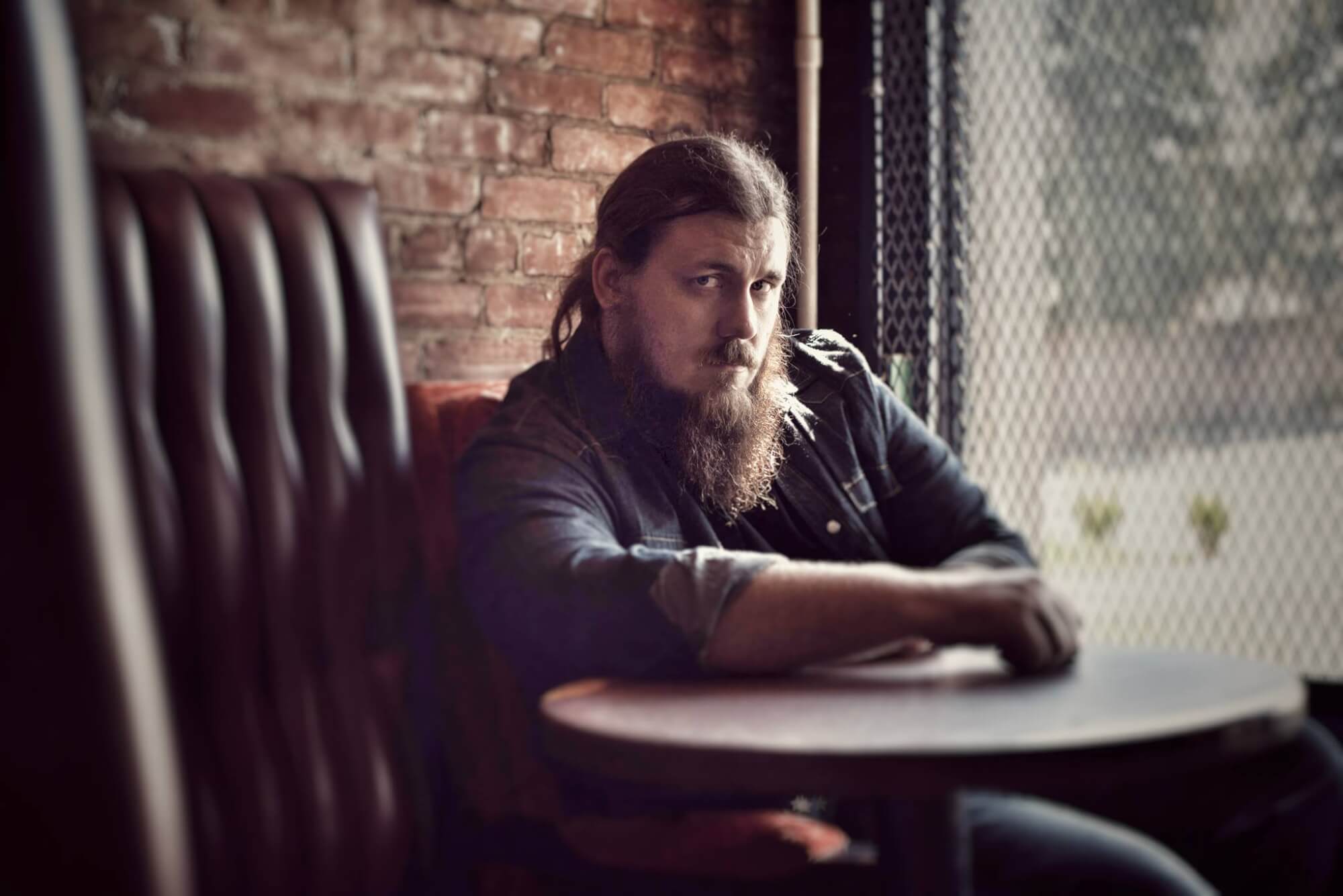 justin wells music press photo sitting at a table