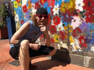 brian zickafoose standing next to art mural wearing mountain music festival shirt
