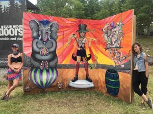 mural created by visual artist team at mountain music festival 2019 with ashton hill and leslie caneda standing next to it