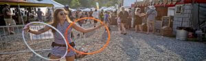 girl with hula hoops on vendor lane at mountain music festival in west virginia