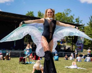 Girl performer with stilt and wings at mountain music festival 2021