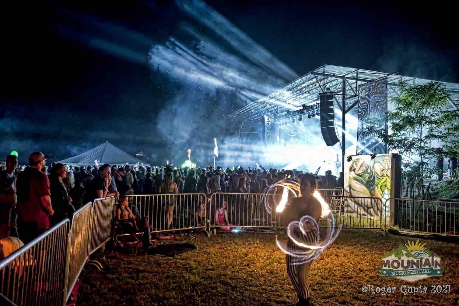 mountain music festival stage in lights with fire performer